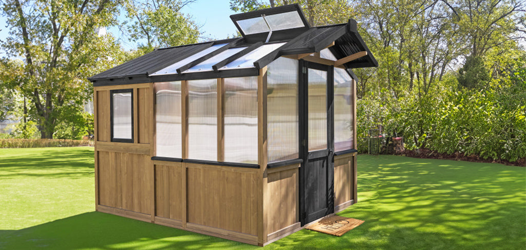 Exterior view of Yardistry Meridian Greenhouse with cedar base walls, double-wall polycarbonate panels, automatic roof vent, and black aluminum frame installed in a backyard